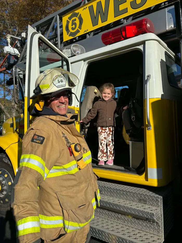 A child visiting a fire truck with a firefighter