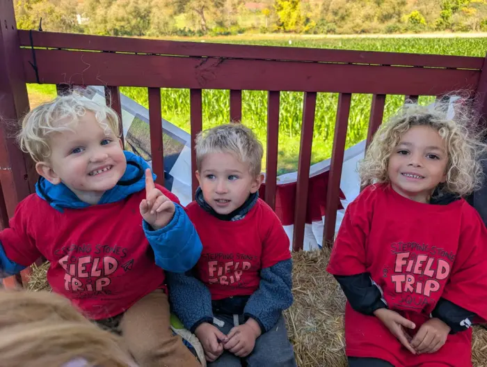 Three children sitting together on a bench during a field trip