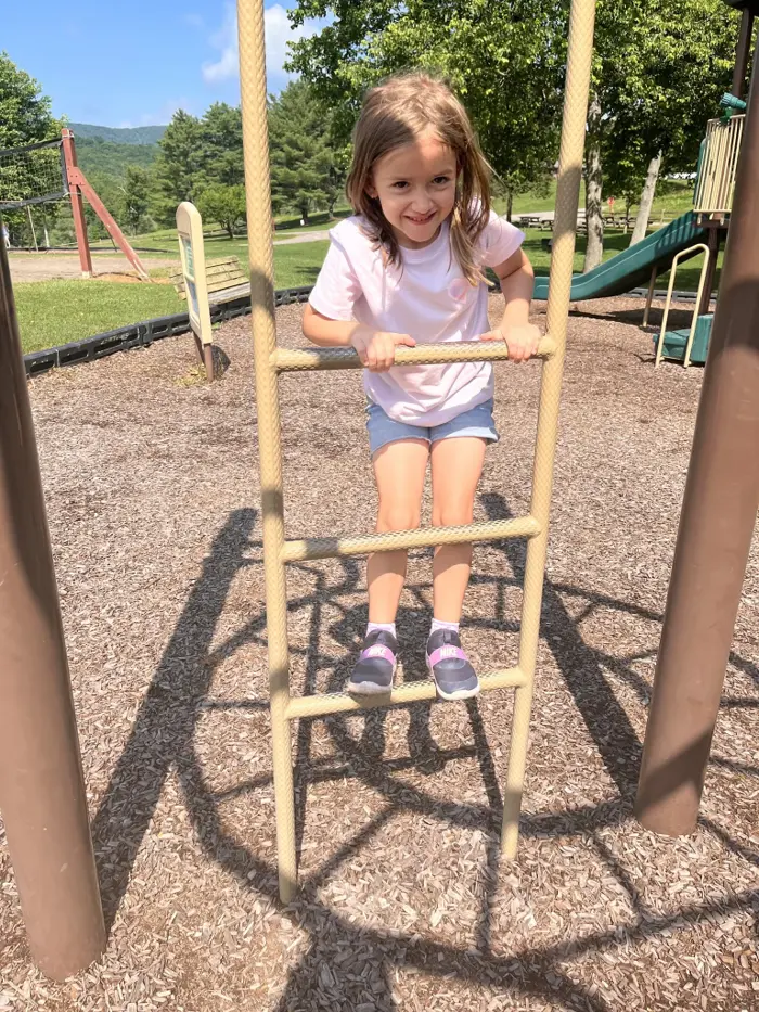 A child climbing a rope ladder on the playground