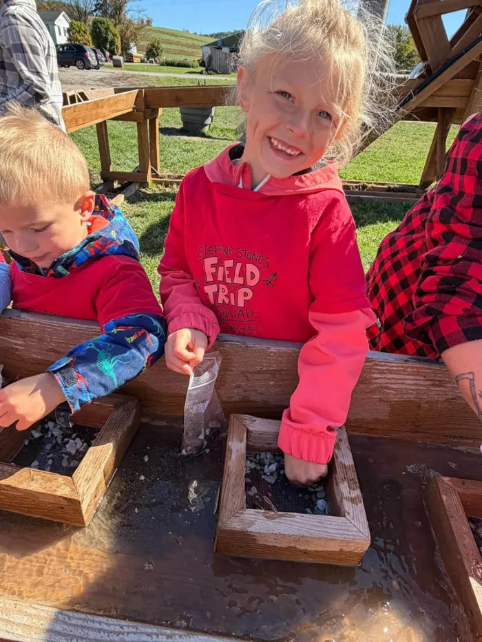 A smiling child exploring an outdoor water activity during a field trip